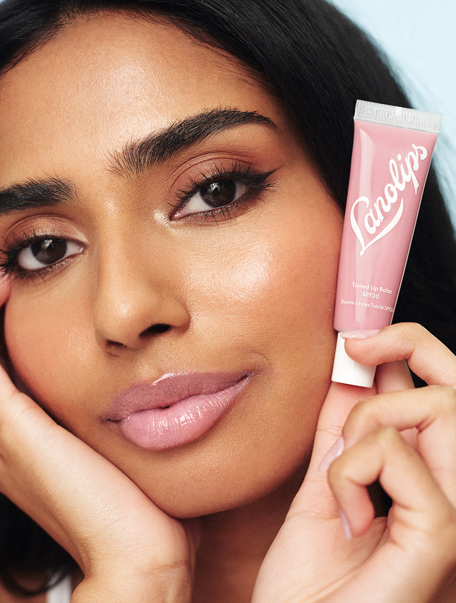 Model wearing and holding Lanolips Tinted Lip Balm SPF30 in Rose