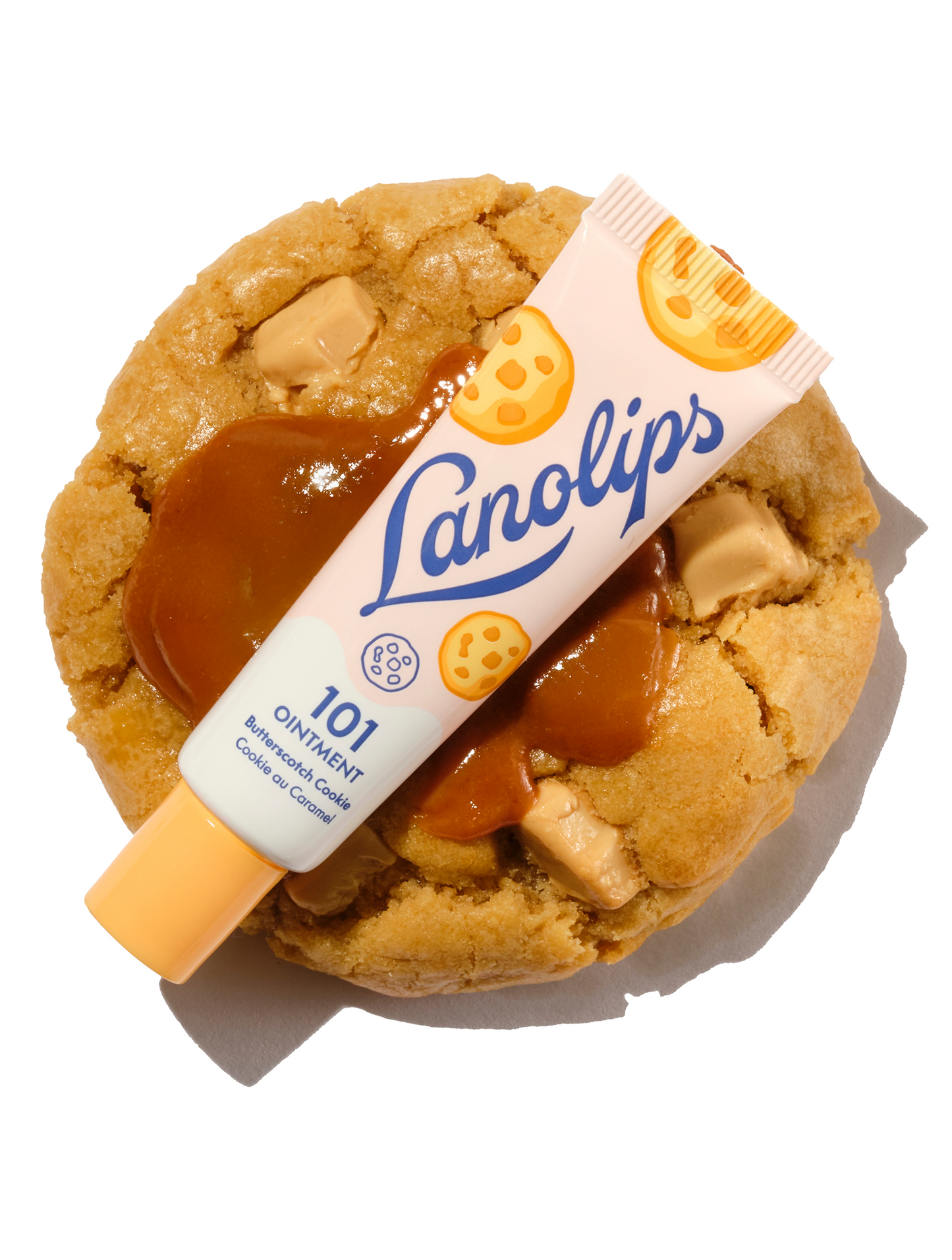 Lanolips 101 Multi-Balm Ointment in Butterscotch Cookie flavour, part of the 101 Delicious collection. The 100% natural lanolin tube is placed over a thick, freshly baked biscuit topped with golden, gooey caramel for deep, lips-loving hydration.