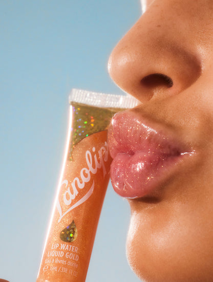 Model holding lanolips liquid lanolin lip water liquid gold in her hand.
