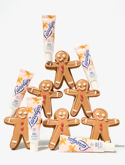 Gingerbread men cookies with Lanolips 101 Ointment Multi-Balm Gingerbread lip balm tubes on a white background.